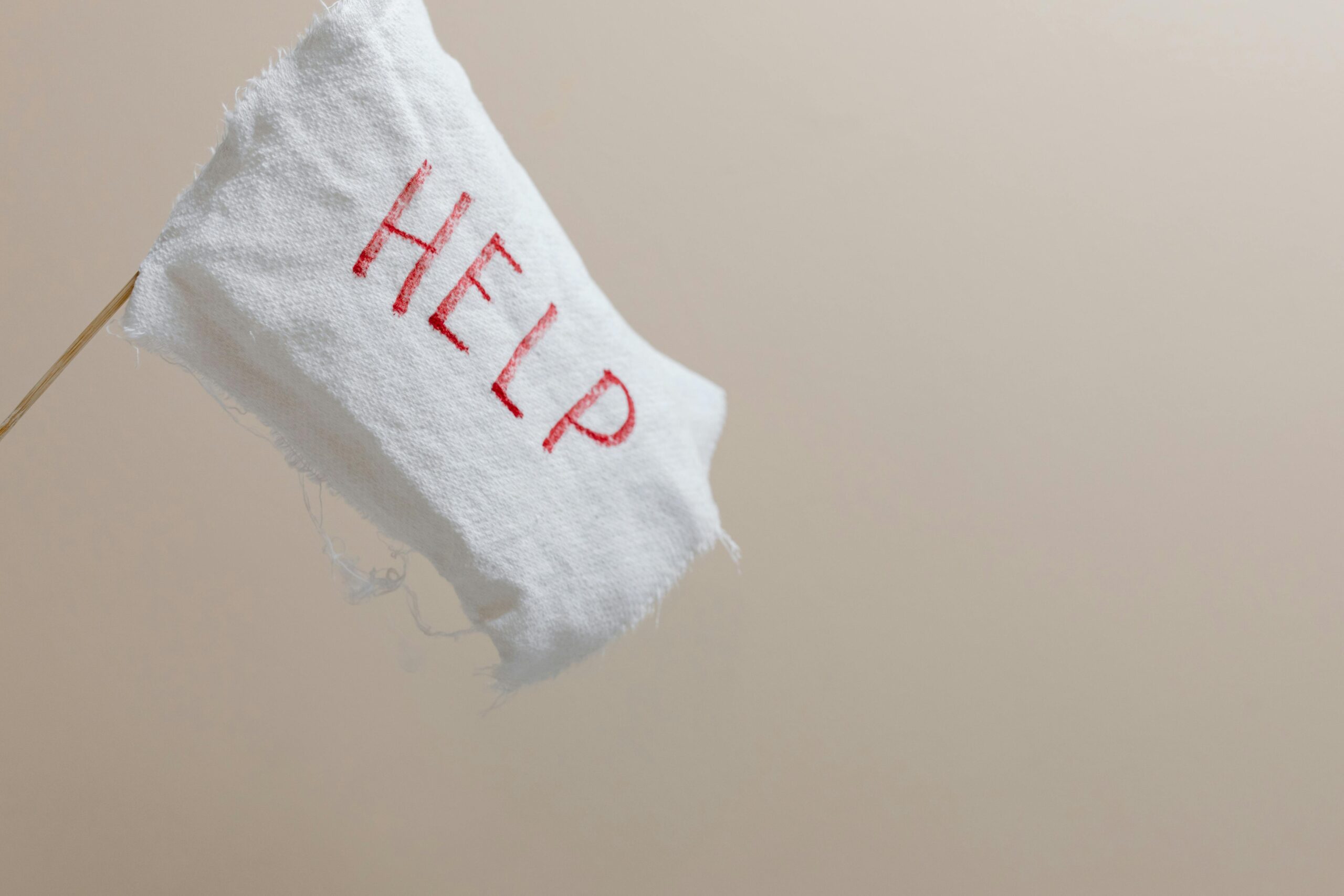A white flag with 'HELP' displayed on a beige background, symbolic of seeking assistance.